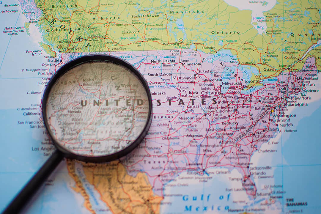 A magnifying glass over a US map highlighting the western region.